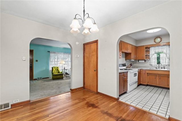 146 Samuel St, Chippewa Twp, PA 15010 - kitchen with white electric stove, open shelves, light wood-type flooring, light countertops, and arched walkways