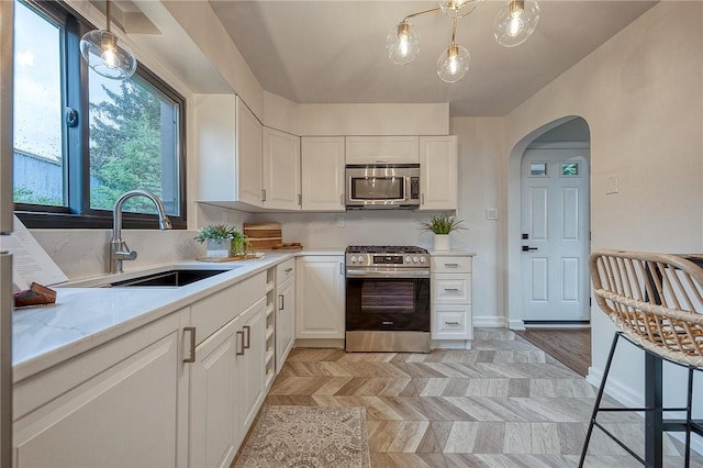 2425 W Pike St, Chartiers, PA 15342 - kitchen featuring appliances with stainless steel finishes, a sink, arched walkways, light countertops, and white cabinets