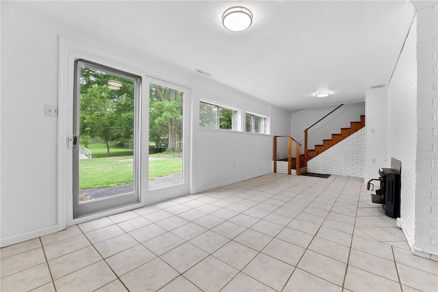 121 Edgar Ln, Peters Twp, PA 15367 - unfurnished living room featuring light tile patterned floors, stairs, brick wall, a wood stove, and baseboards