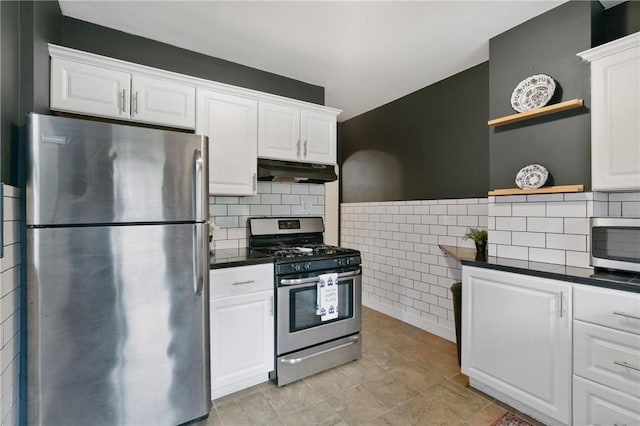 908 N Saint Clair St, Highland Park, PA 15206 - kitchen featuring appliances with stainless steel finishes, under cabinet range hood, open shelves, dark countertops, and tile walls