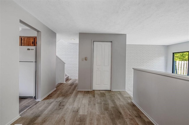 3143 Camberly Dr, Hampton, PA 15044 - hallway with a textured ceiling, wood finished floors, brick wall, and baseboards