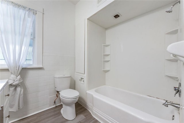 1030 N Grandview Ave, Mckeesport, PA 15132 - bathroom featuring toilet, wood finished floors, tile walls, shower / washtub combination, and vanity