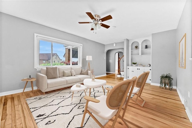 2140 Carolina Ave, West Mifflin, PA 15122 - living area featuring arched walkways, a ceiling fan, light wood-style flooring, baseboards, and built in shelves