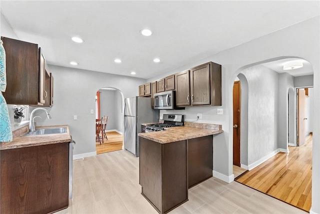 2140 Carolina Ave, West Mifflin, PA 15122 - kitchen featuring appliances with stainless steel finishes, arched walkways, a sink, dark brown cabinetry, and light wood-style flooring