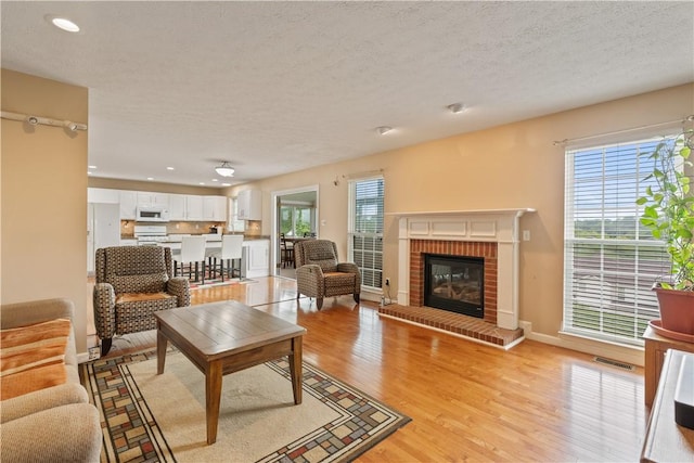 5109 Forest Ridge Dr, South Fayette, PA 15057 - living room with light wood-type flooring, recessed lighting, a brick fireplace, baseboards, and a textured ceiling