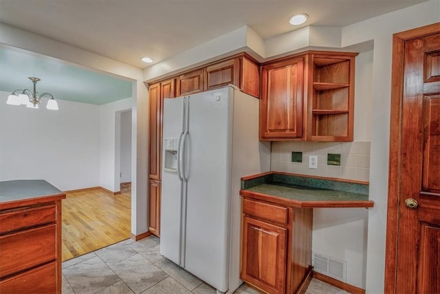 200 Spartan Dr, Bethel Park, PA 15102 - kitchen featuring white refrigerator with ice dispenser, dark countertops, brown cabinets, a chandelier, and tasteful backsplash