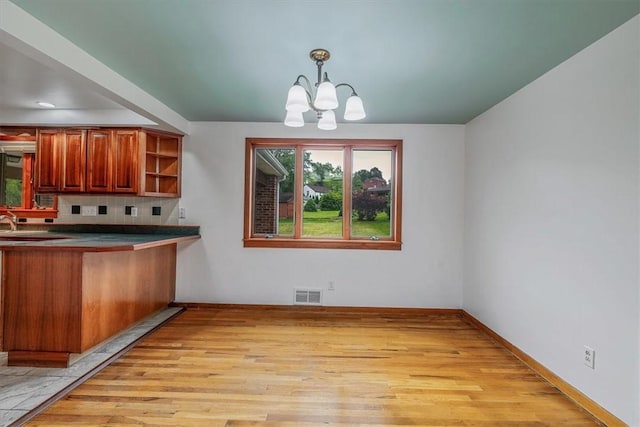 200 Spartan Dr, Bethel Park, PA 15102 - kitchen featuring a chandelier, light wood-style flooring, brown cabinets, tasteful backsplash, and decorative light fixtures