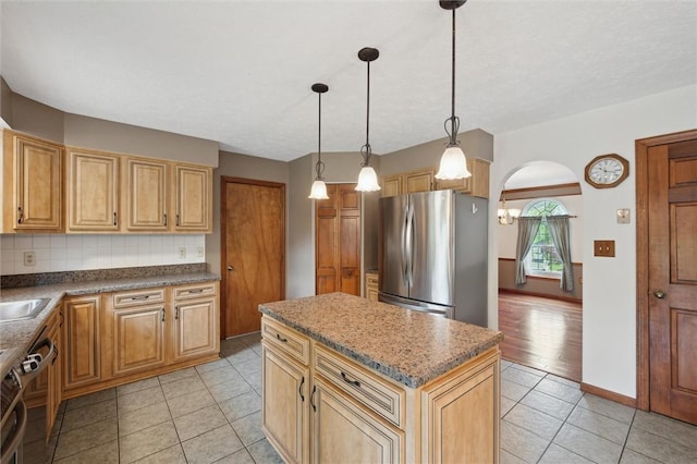 5020 Meadow Crest Dr, Hampton, PA 15101 - kitchen featuring appliances with stainless steel finishes, a kitchen island, light tile patterned flooring, arched walkways, and backsplash