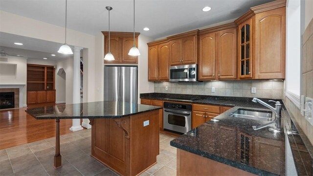 203 Providence Ct, Adams Twp, PA 16059 - kitchen featuring appliances with stainless steel finishes, a sink, brown cabinetry, glass insert cabinets, and a breakfast bar