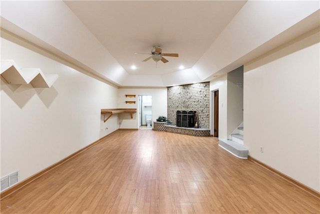 2352 Edgar St, Carrick, PA 15210 - unfurnished living room featuring a ceiling fan, a brick fireplace, a tray ceiling, light wood finished floors, and stairs