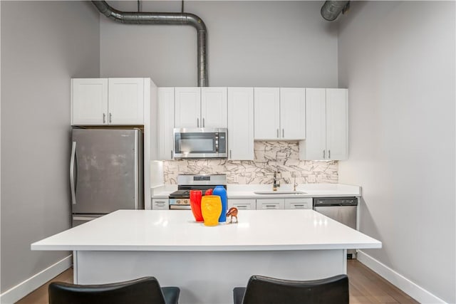 622 Gross St Unit 104, Bloomfield, PA 15224 - kitchen featuring appliances with stainless steel finishes, a sink, a breakfast bar, tasteful backsplash, and baseboards