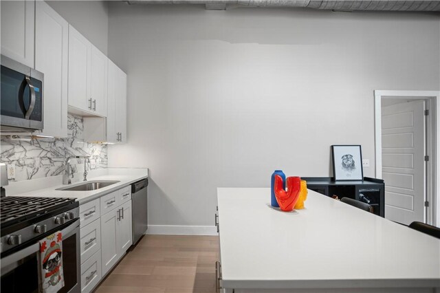 622 Gross St Unit 104, Bloomfield, PA 15224 - kitchen with stainless steel appliances, a sink, backsplash, light countertops, and baseboards