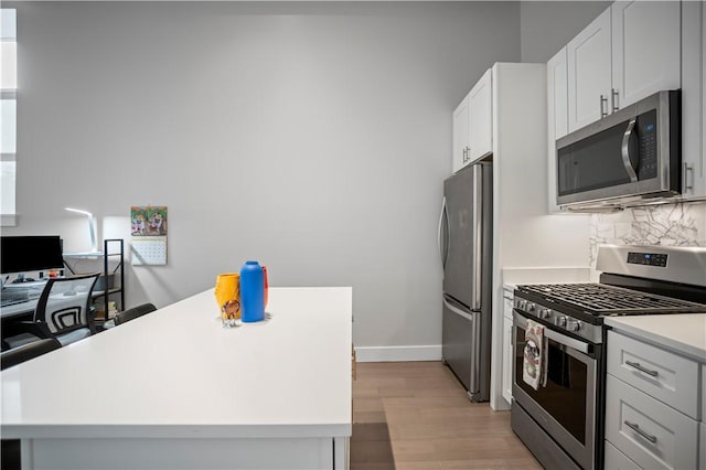 622 Gross St Unit 104, Bloomfield, PA 15224 - kitchen with stainless steel appliances, light wood-type flooring, light countertops, white cabinets, and backsplash
