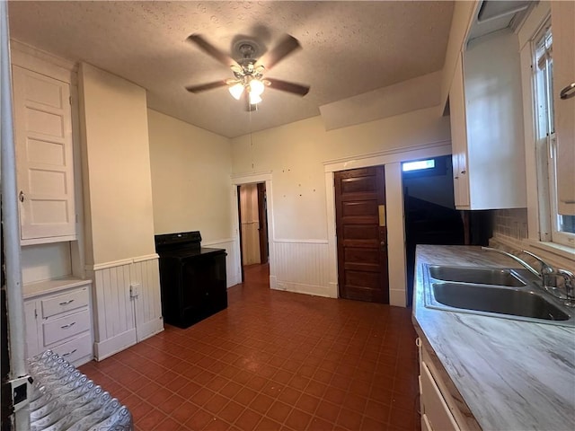 150 Euclid Ave, Sharon, PA 16146 - kitchen featuring a wainscoted wall, ceiling fan, white cabinetry, light countertops, and a textured ceiling