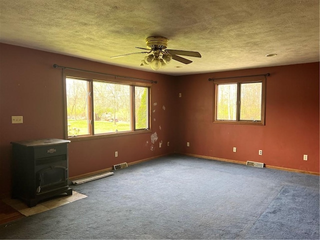 88 Fleming Rd, Pine Twp Mer, PA 16127 - carpeted empty room featuring a wood stove, a ceiling fan, plenty of natural light, a textured ceiling, and baseboards