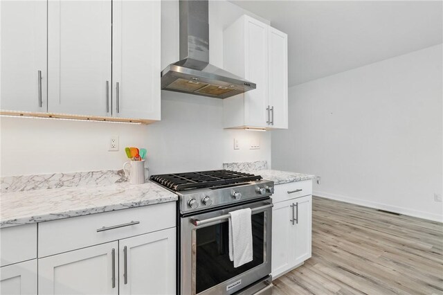 5523 Butler St, Lawrenceville, PA 15201 - kitchen with stainless steel gas range oven, wall chimney exhaust hood, baseboards, white cabinets, and light wood-type flooring