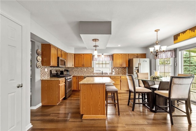 5743 Villahaven Dr, Bethel Park, PA 15236 - kitchen featuring stainless steel appliances, a center island, dark wood finished floors, backsplash, and a kitchen breakfast bar