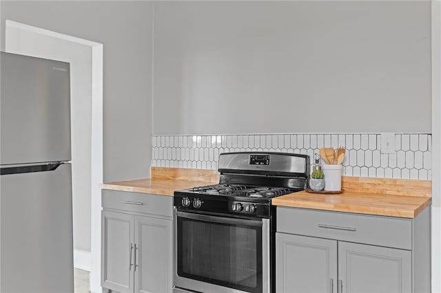 1222 Forest Ave, New Kensington, PA 15068 - kitchen with appliances with stainless steel finishes, butcher block counters, gray cabinetry, backsplash, and baseboards