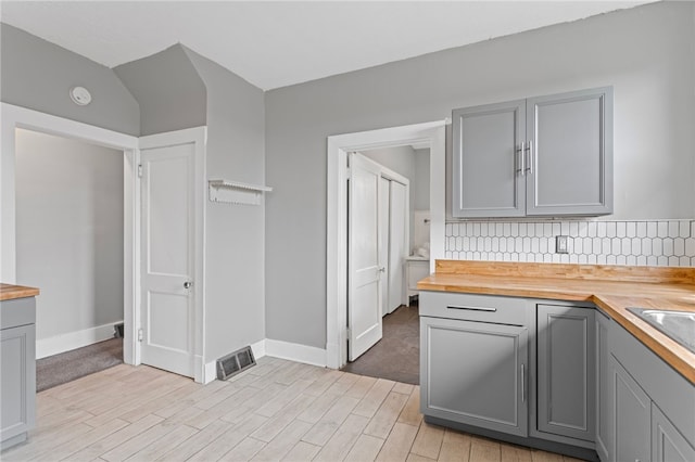 1222 Forest Ave, New Kensington, PA 15068 - kitchen featuring gray cabinetry, wooden counters, backsplash, light wood-type flooring, and baseboards