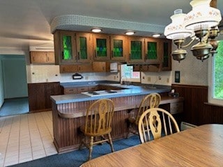 1877 Main St, Arona, PA 15617 - kitchen with wainscoting, a peninsula, glass insert cabinets, a chandelier, and a breakfast bar