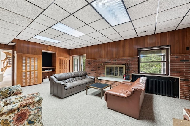 428 Jefferson School Rd, Cook Twp, PA 15658 - living room with wood walls, a fireplace, carpet, a drop ceiling, and radiator