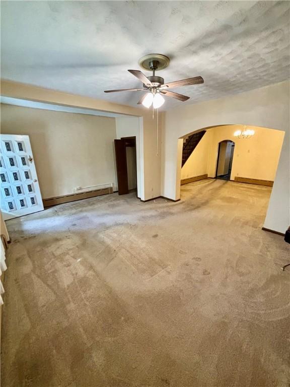 7027 Blackhawk St, Swissvale, PA 15218 - unfurnished living room featuring arched walkways, light colored carpet, a ceiling fan, a baseboard heating unit, and baseboards