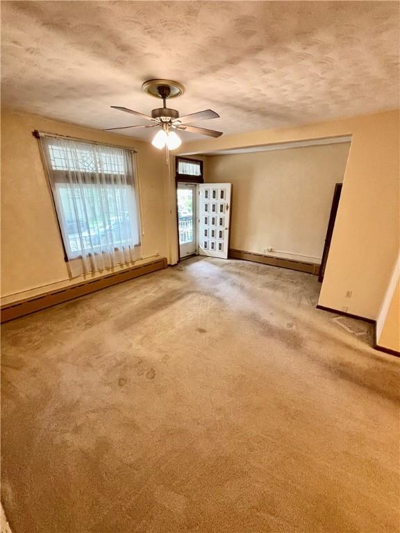 7027 Blackhawk St, Swissvale, PA 15218 - spare room featuring baseboard heating, a ceiling fan, a textured ceiling, baseboards, and french doors