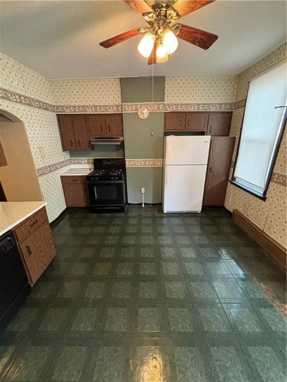 7027 Blackhawk St, Swissvale, PA 15218 - kitchen featuring freestanding refrigerator, black gas range, wallpapered walls, dishwashing machine, and light countertops