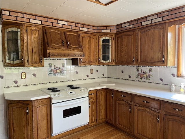 100 Rohaley Ln, Menallen Twp, PA 15480 - kitchen with white range with electric stovetop, decorative backsplash, light countertops, brown cabinetry, and glass insert cabinets