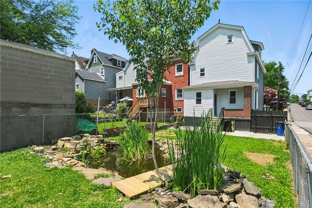 134 Poplargrove St, Carrick, PA 15210 - back of property with a fenced backyard, brick siding, a gambrel roof, and a garden pond