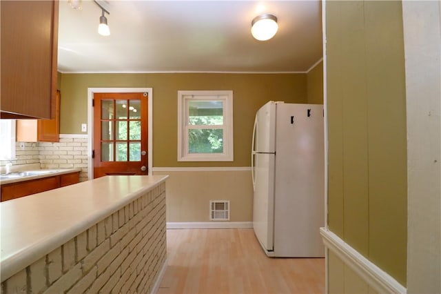 1818 Bluff St, West Mifflin, PA 15122 - kitchen featuring freestanding refrigerator, light wood finished floors, light countertops, brown cabinets, and tasteful backsplash