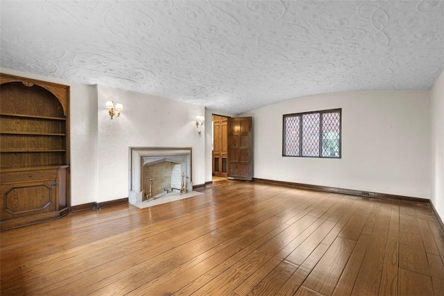 1 Robin Rd, Squirrel Hill, PA 15217 - unfurnished living room featuring a textured ceiling, baseboards, wood-type flooring, lofted ceiling, and a premium fireplace