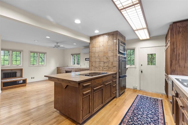 1 Robin Rd, Squirrel Hill, PA 15217 - kitchen featuring black appliances, a peninsula, an AC wall unit, light wood-style floors, and radiator heating unit