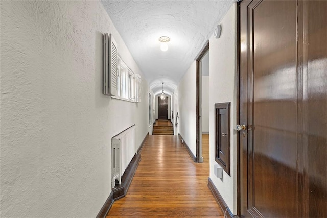1 Robin Rd, Squirrel Hill, PA 15217 - hall featuring a textured wall, wood finished floors, a textured ceiling, radiator heating unit, and baseboards
