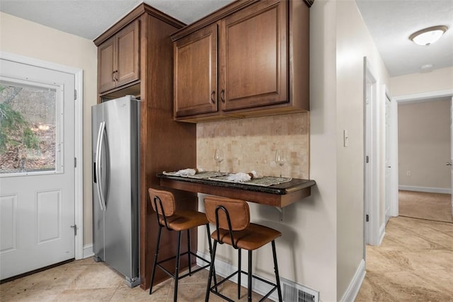 600 Camp Meeting Rd, Leet Twp, PA 15143 - kitchen featuring stainless steel refrigerator with ice dispenser, backsplash, baseboards, dark countertops, and a breakfast bar area