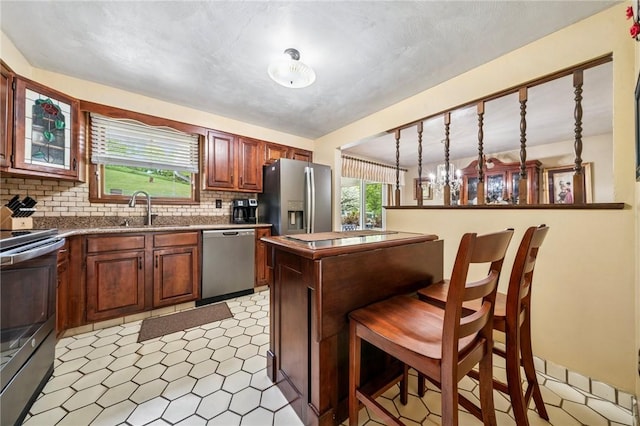 1967 Rostraver, Rostraver, PA 15012 - kitchen with appliances with stainless steel finishes, a sink, light floors, a kitchen breakfast bar, and tasteful backsplash