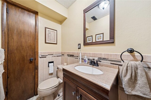 1967 Rostraver, Rostraver, PA 15012 - bathroom featuring vanity, tile walls, toilet, and a wainscoted wall