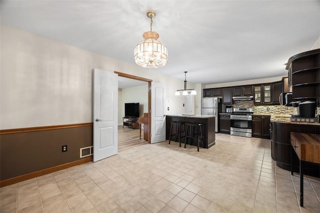 803 E Arcadia Dr, Mccandless, PA 15237 - kitchen featuring appliances with stainless steel finishes, a chandelier, under cabinet range hood, a breakfast bar area, and backsplash