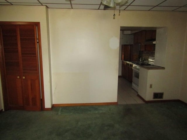 1214 1/2 3rd St, Mckees Rocks, PA 15136 - kitchen with a drop ceiling, light carpet, under cabinet range hood, dark countertops, and baseboards
