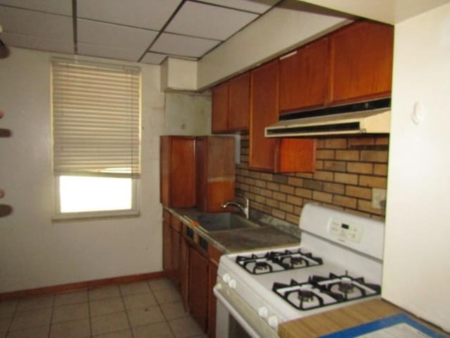 1214 1/2 3rd St, Mckees Rocks, PA 15136 - kitchen with white gas range, under cabinet range hood, tasteful backsplash, baseboards, and a sink
