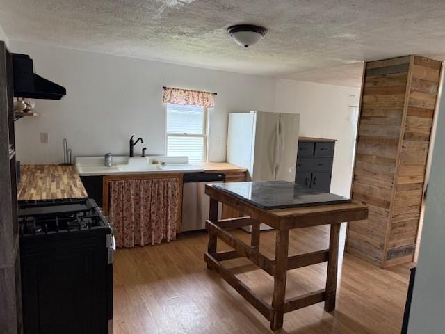 15 Miner Ave, Bentleyville, PA 15314 - kitchen with stainless steel dishwasher, black gas stove, freestanding refrigerator, light wood-style flooring, and exhaust hood