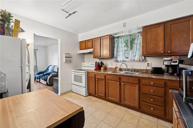 233 6th St, California, PA 15419 - kitchen featuring white appliances, a sink, under cabinet range hood, brown cabinetry, and dark countertops