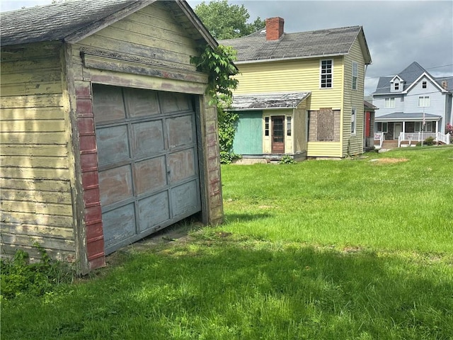 112 Laughlin St, Dawson, PA 15428 - back of property featuring a chimney, a detached garage, a lawn, and an outbuilding