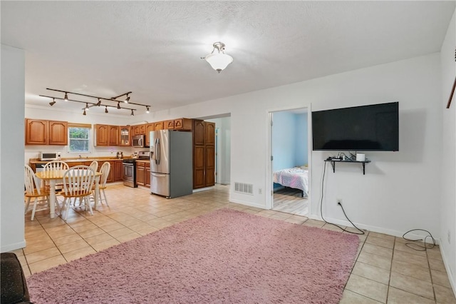 2883 Wilson St N, Franklin Twp, PA 15301 - kitchen featuring stainless steel appliances, light tile patterned floors, brown cabinetry, baseboards, and track lighting