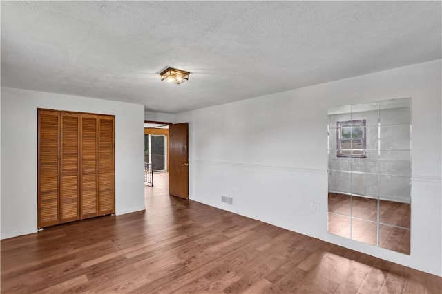 309 Delaware N, Versailles, PA 15137 - unfurnished bedroom with wood finished floors, a textured ceiling, a closet, multiple windows, and ensuite bathroom