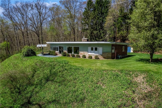 541 W Danville Rd, Oakland Twp, PA 16025 - rear view of house featuring stone siding, a yard, a wooded view, and a chimney