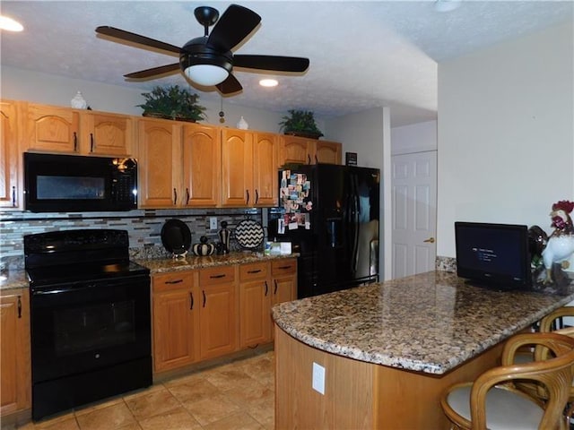 403 Shannon Dr, South Union Twp, PA 15401 - kitchen with black appliances, a peninsula, decorative backsplash, a kitchen bar, and stone countertops