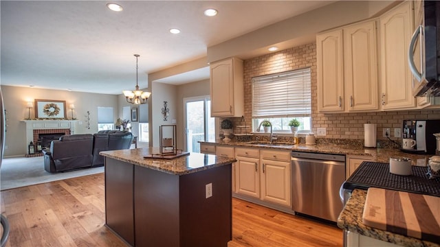 104 Cherokee Ct, Buffalo Twp But, PA 16229 - kitchen with stainless steel appliances, a sink, a center island, a fireplace, and light wood-style flooring