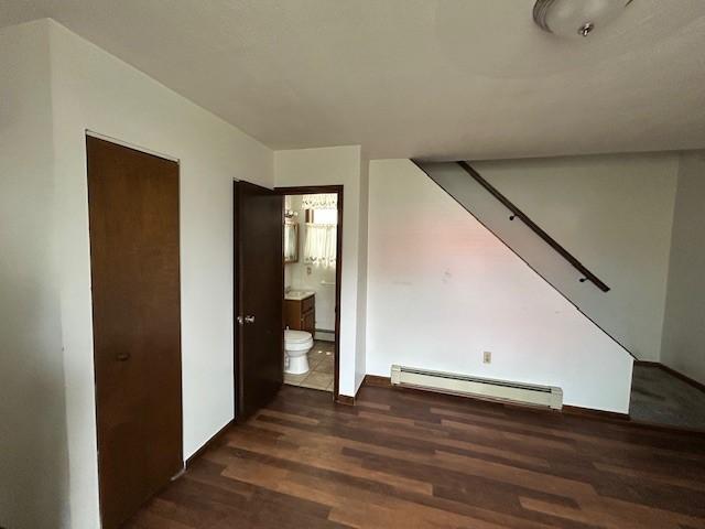 735 Park Ave, Johnstown, PA 15902 - unfurnished bedroom featuring a baseboard heating unit, wood finished floors, connected bathroom, and baseboards