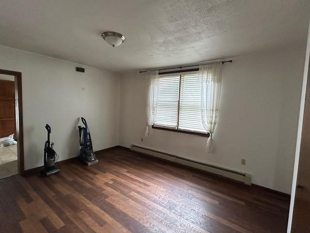 735 Park Ave, Johnstown, PA 15902 - empty room featuring a baseboard heating unit, dark wood finished floors, and a textured ceiling